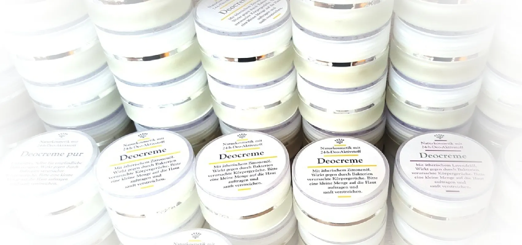 Mehrere Tiegel Deocreme von der Naturseifen Manufaktur Uckermark, in verschiedenen Sorten wie Pur, Zitrone und Lavendel, ordentlich gestapelt.